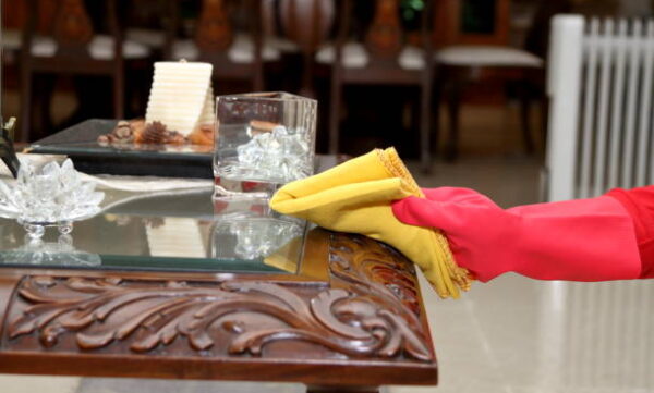 Dusting and cleaning with yellow fabric duster while wearing red color rubber gloves.